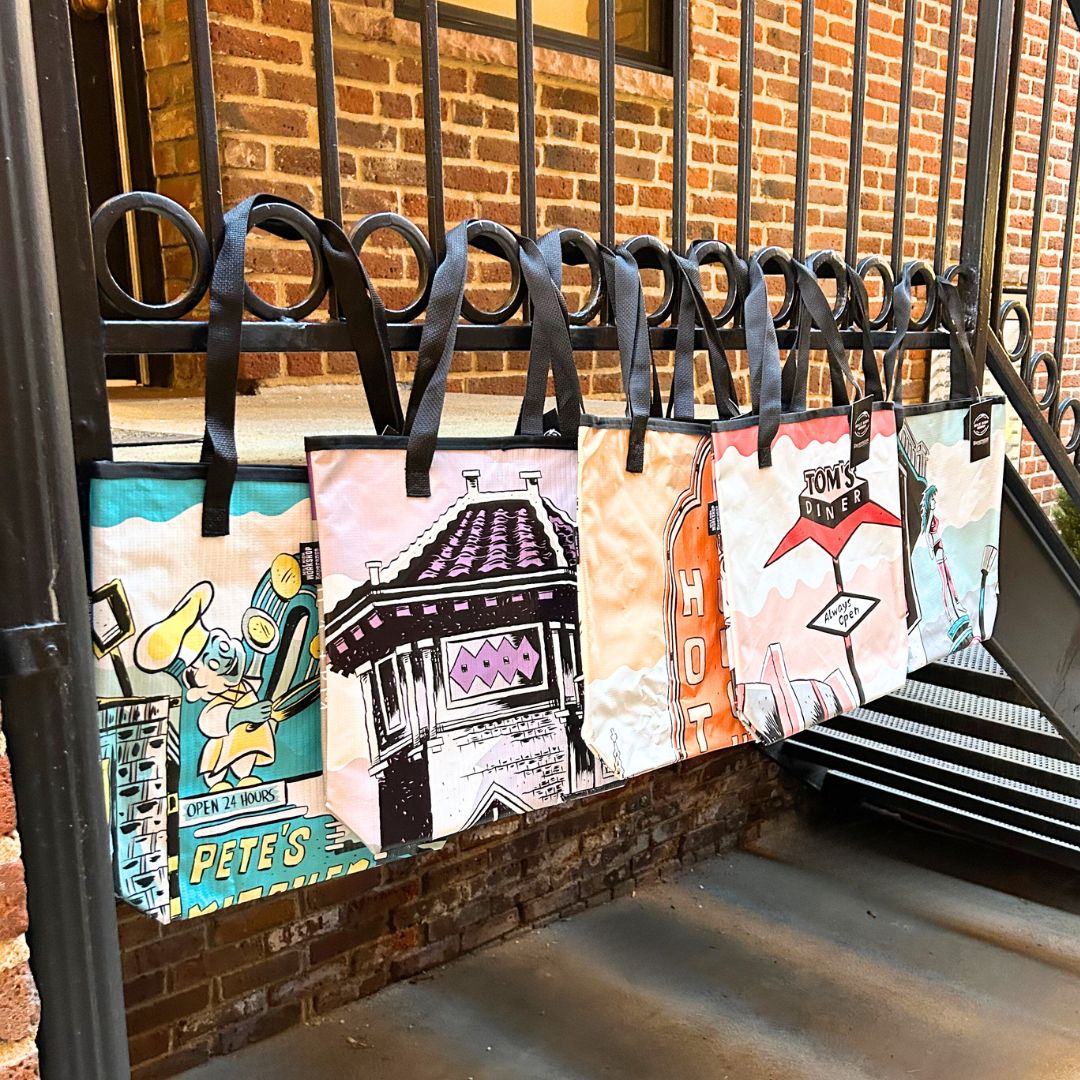 five tote bags hanging from a railing